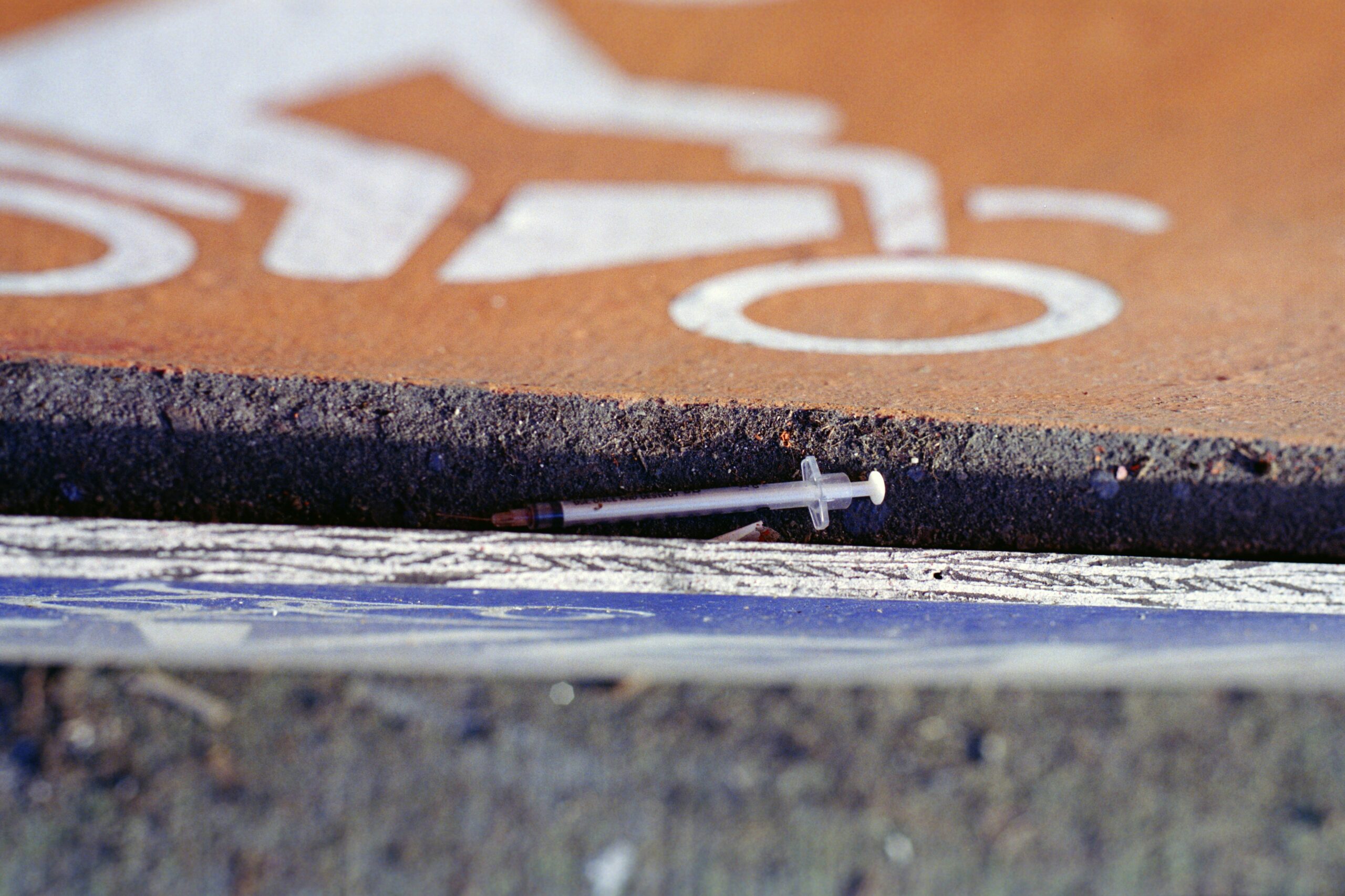 A syringe that is used for shooting up heroin, lying on the street.